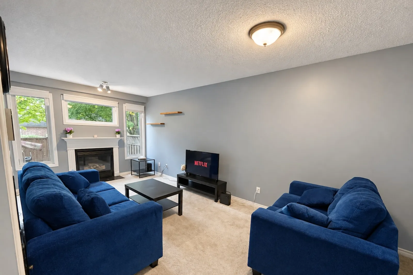 Living room with two blue sofas, a coffee table, a television and a gas fireplace