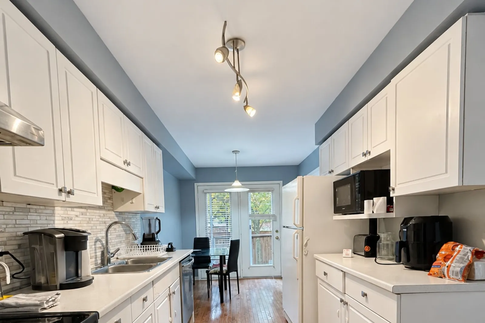 Galley kitchen with white cabinets, a coffee machine and full-size appliances