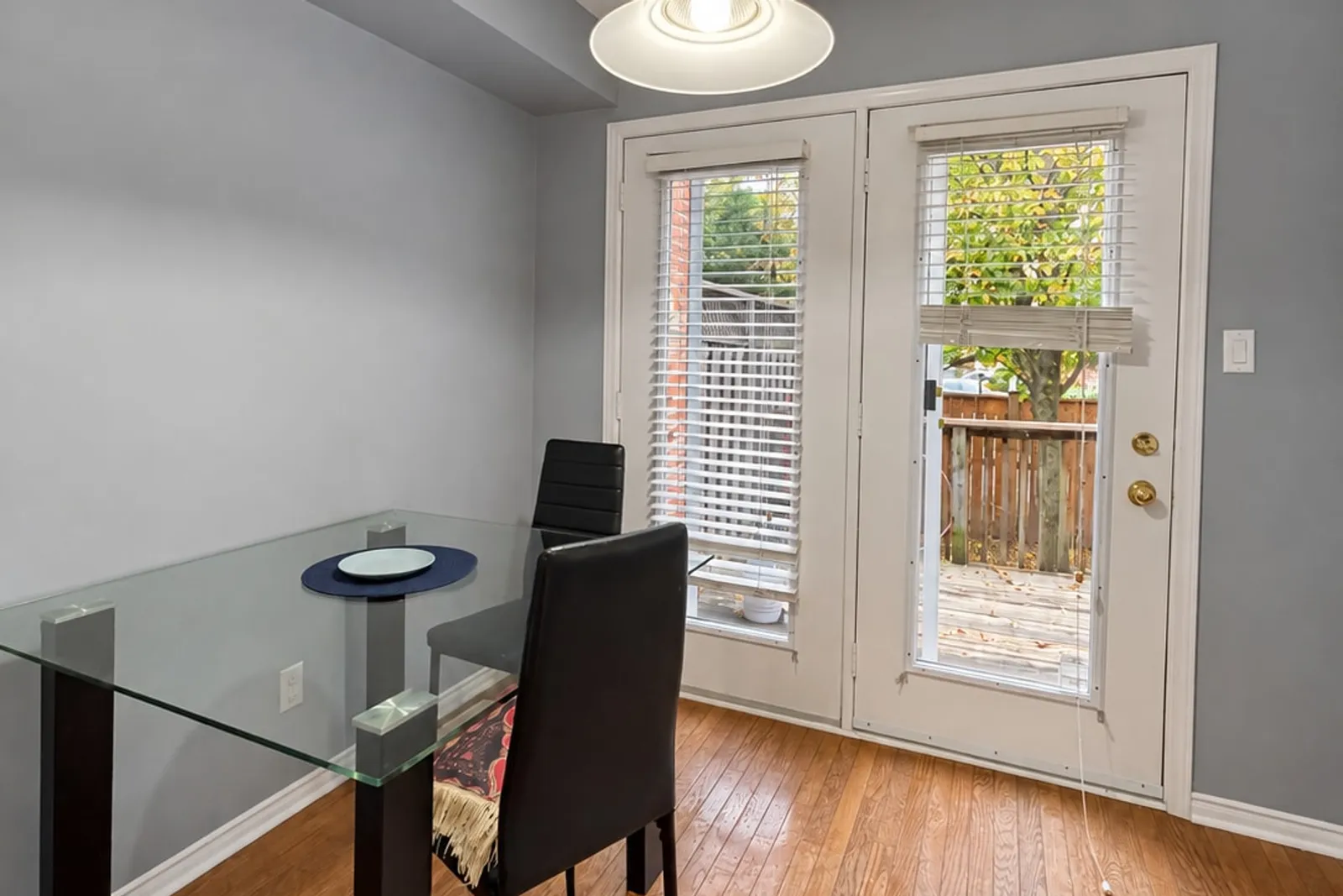 Glass dining table beside French doors that open onto the backyard deck