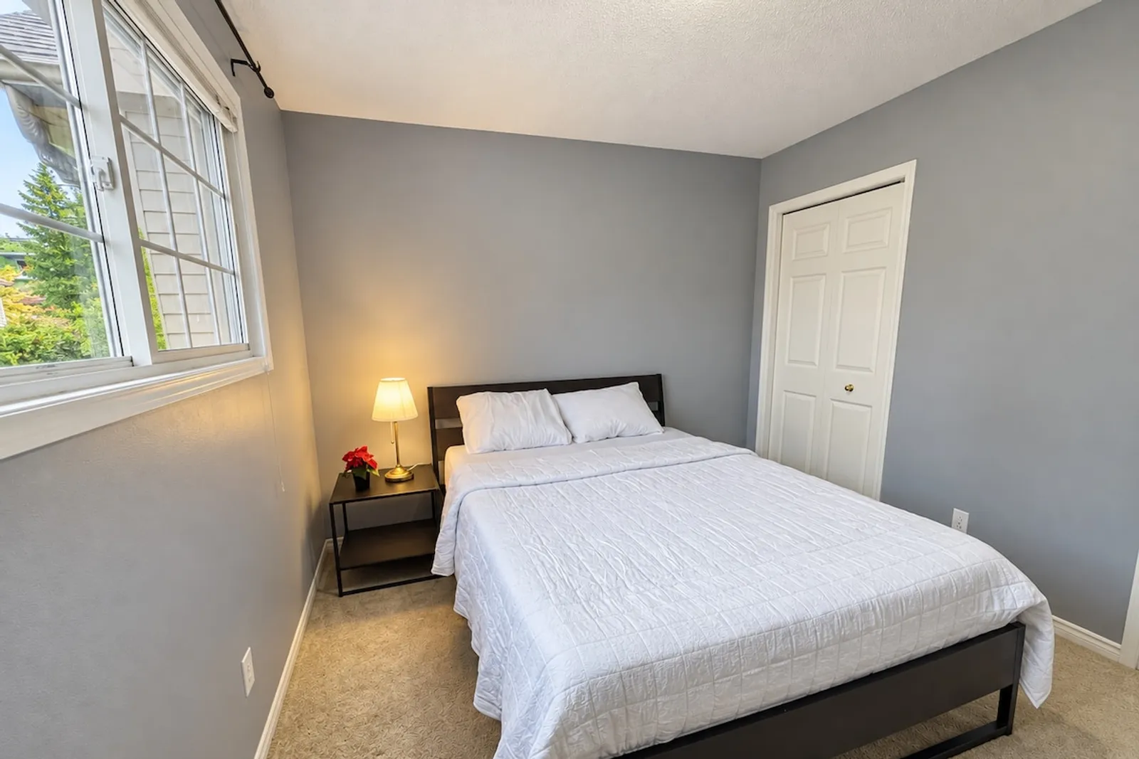 First bedroom with a queen bed, bedside lamp and closet