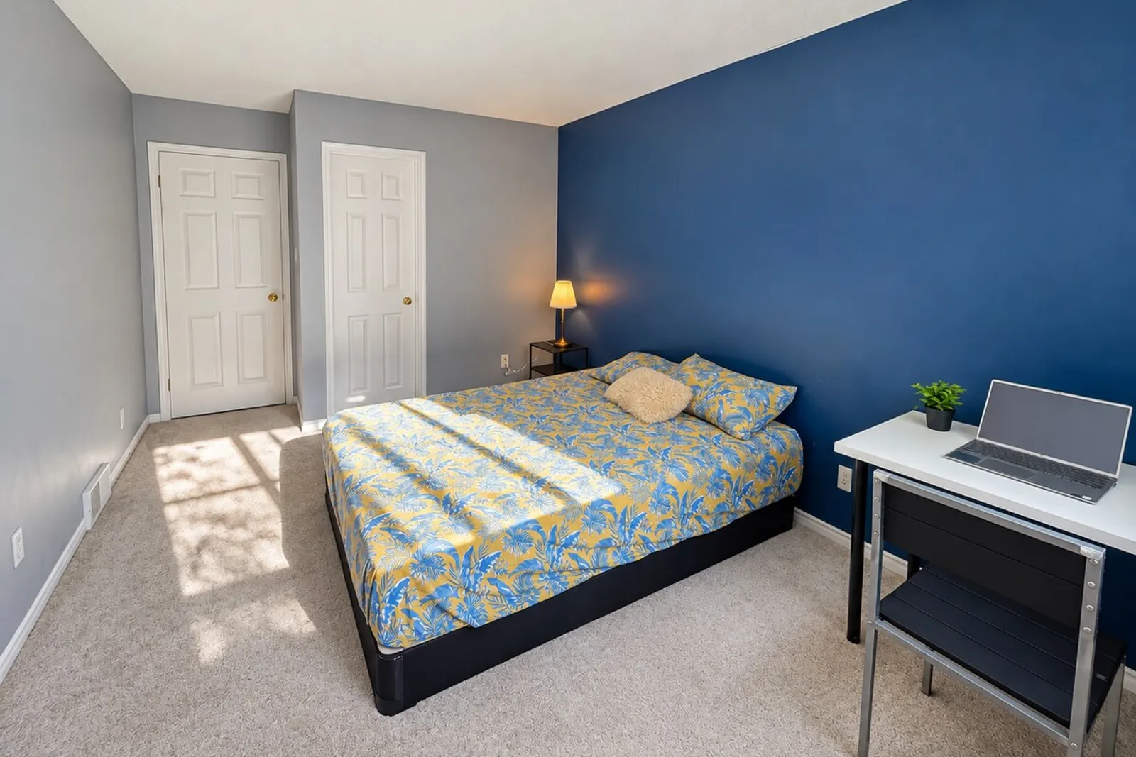 Second bedroom with a queen bed, a blue feature wall and a desk