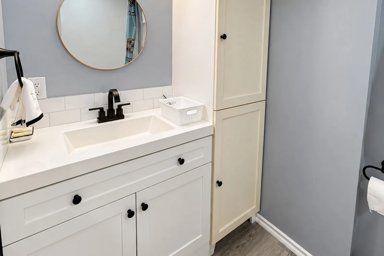 Bathroom vanity with a round mirror and storage cabinet